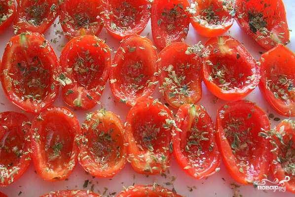 Затем помидоры раскладываем на противень, застеленный бумагой для выпекания. Помидоры поливаем оливковым маслом, посыпаем орегано, перцем. Затем добавляем либо рубленный чеснок, либо выдавленный. 