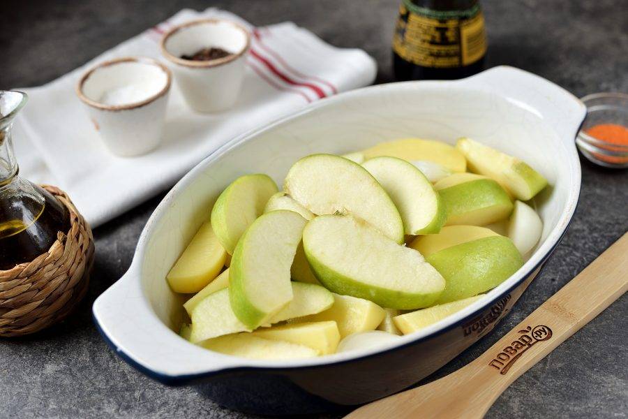 Нарежьте картофель четвертинками, яблоко почистите от сердцевины, нарежьте вместе с луком и чесноком, переложите в огнеупорную форму. 