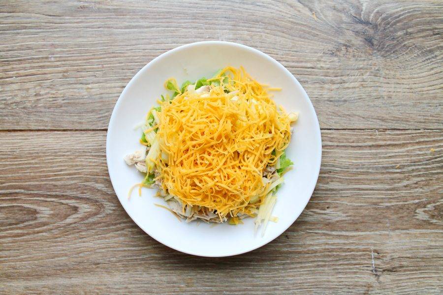 Сыр натрите на средней терке, выложите в салатник с фруктами и салатными листьями.