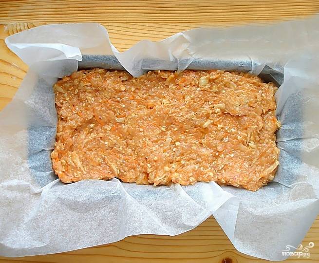 Все тщательно перемешиваем. Для выпекания мясного хлебя нам понадобится форма под выпечку. Выстилаем хлебную форму пергаментной бумагой. Выкладываем фарш внутрь и разравниваем. Смазываем верхушку томатным соусом.