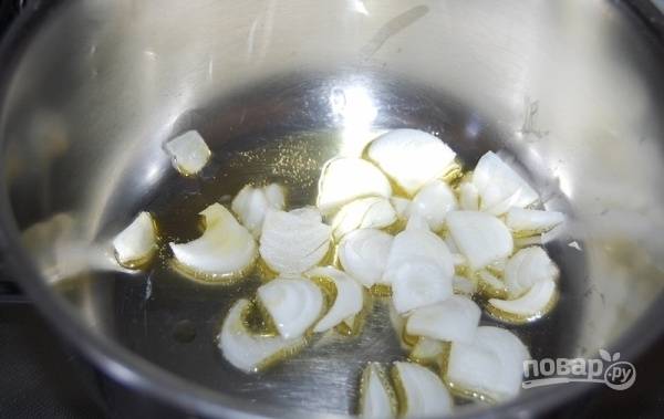 Картофель и лук почистите и промойте под холодной проточной водой. Репчатый лук нарежьте ломтиками и обжарьте в толстостенной кастрюле в небольшом количестве оливкового масла.