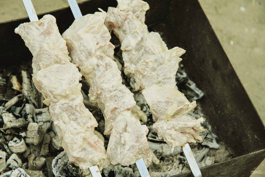 Кусочки маринованного мяса нанизайте на шампура, разместите на мангале и жарьте периодически переворачивая до готовности мяса.