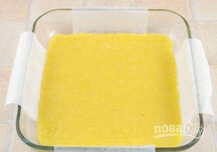 Тесто раскатайте в пласт. Уложите его в форму для выпечки, застеленную пергаментной бумагой. Уберите тесто на 20 минут в холодильник.