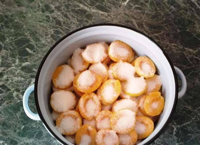 Удалите из плодов косточки, пересыпьте фрукты сахаром и оставьте на несколько часов, чтобы абрикосы пустили сок. 