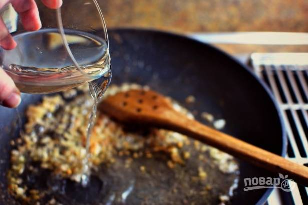 Уберите рыбу, а на оствшемся масле обжарьте до золотистости измельченный лук и чеснок. Затем влейте вино.