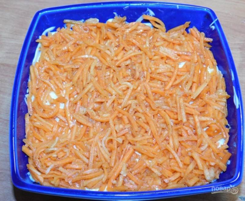 Затем немного порежьте морковь по-корейски. Выложите следующим слоем. Немного смажьте майонезом.