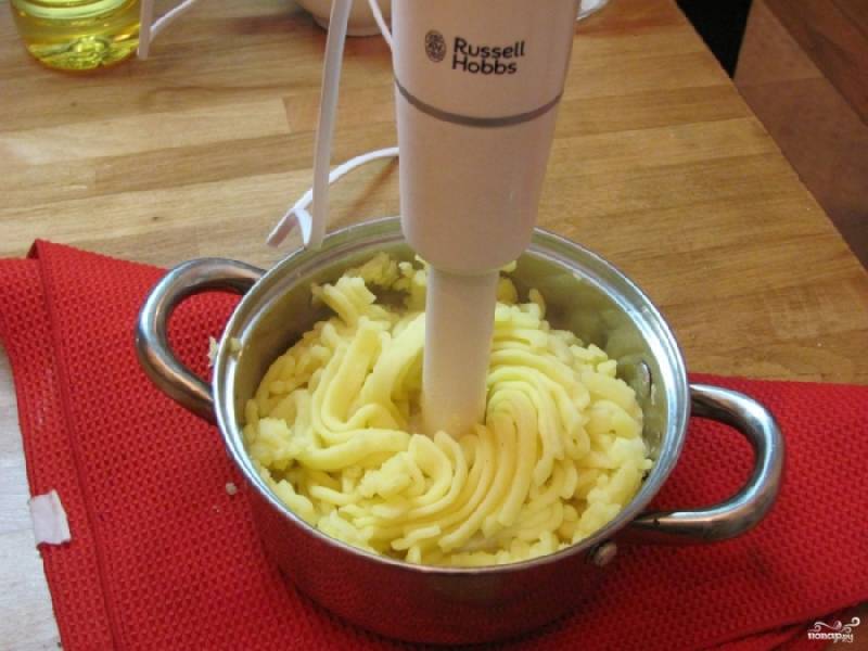 4. Аккуратно измельчите при помощи блендера картошку и зубчики чеснока. Постепенно введите сливочное масло. Продолжайте измельчать блендером до образования пышного пюре. Его густоту регулируйте с помощью картофельно-чесночного отвара.