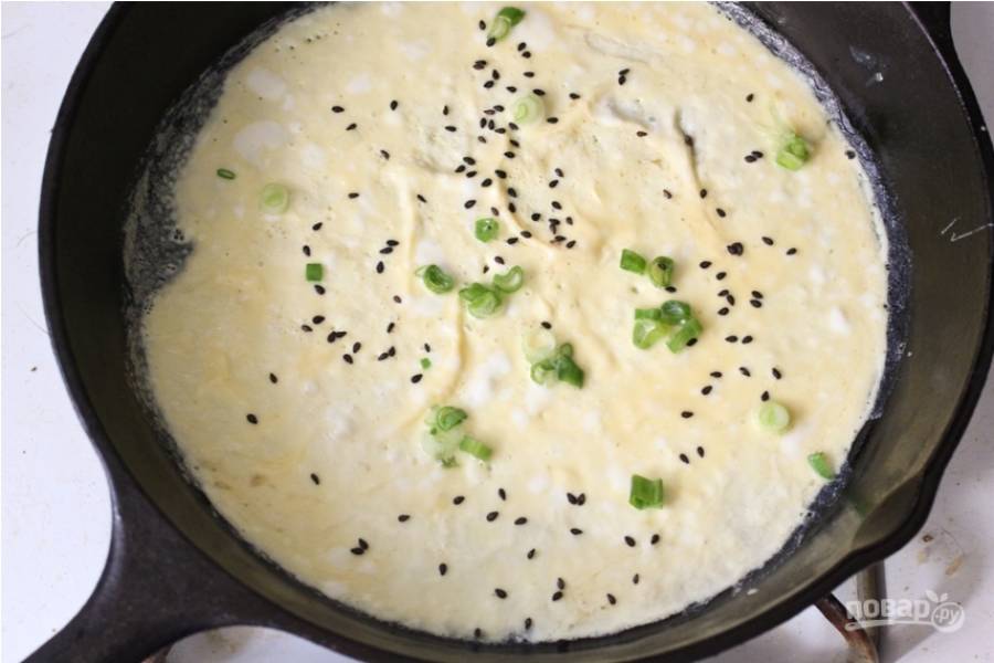 6.	Каждое яйцо разбейте в отдельную миску, добавьте по щепотке соли и перца, размешайте. Обжарьте каждое яйцо на разогретой сковороде, добавьте немного измельченного лука, черный кунжут.