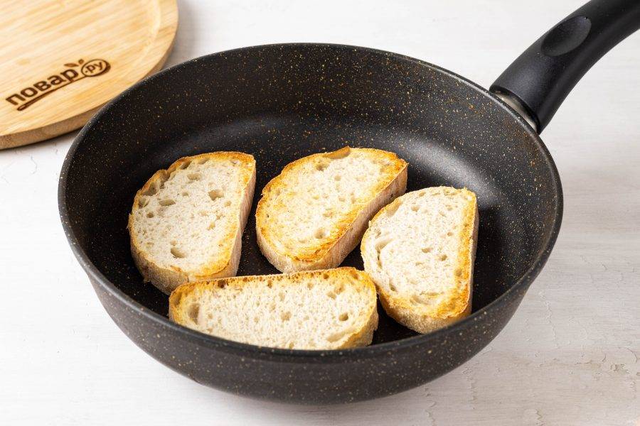 Нарежьте хлеб на ломтики средней толщины. Обжарьте их в сухой сковороде с двух сторон до румяности.