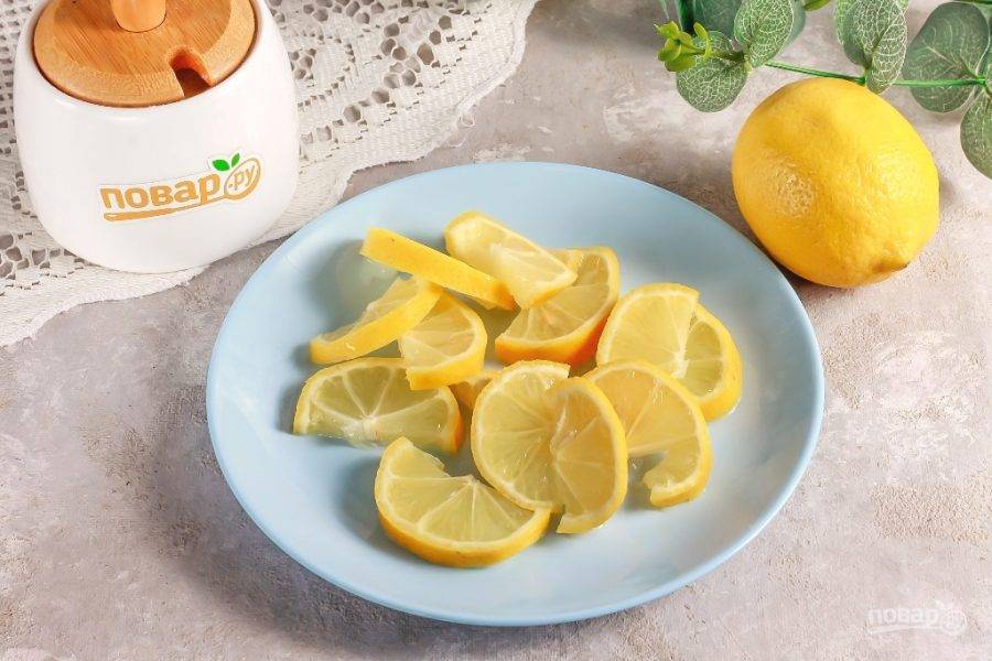 Вскипятите воду в чайнике и ошпарьте все лимоны в течение 1 минуты. Таким образом из фруктов можно удалить горечь. Разрежьте каждый плод на части, затем на ломтики и удалите косточки.