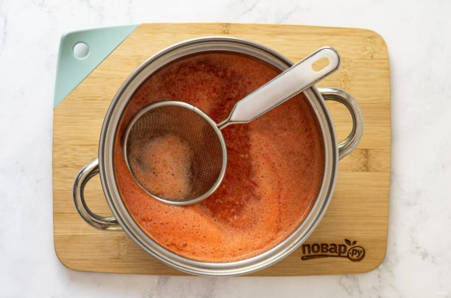 Затем, чтобы сократить время приготовления кетчупа, отделите жидкость от томатной массы. Придавите небольшим ситом измельченные томаты и вычерпните большую часть жидкости.