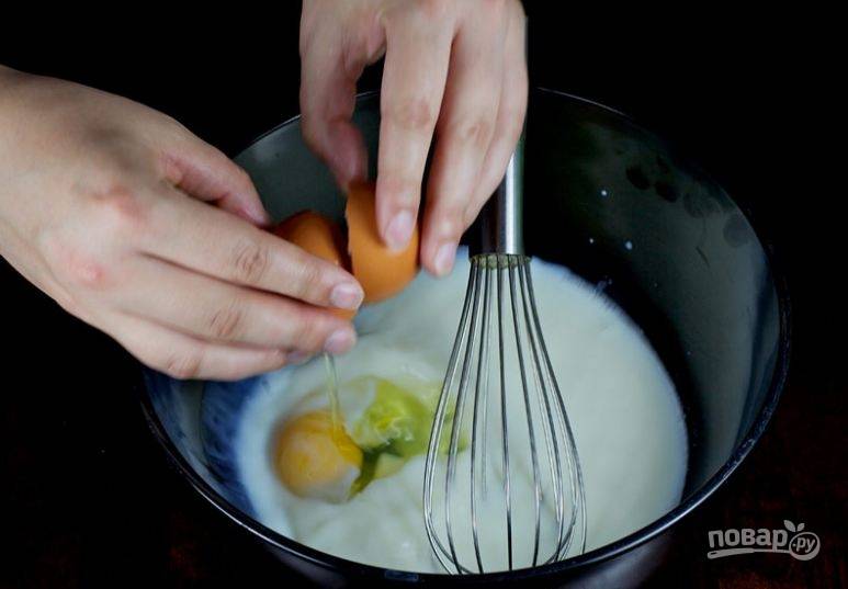 2. Нагрейте молоко до 50-60 градусов. Влейте в большую миску. Вбейте туда же яйца и насыпьте оставшийся сахар. Хорошо размешайте с помощью венчика. Добавьте охлажденное топленное сливочное масло и снова размешайте.