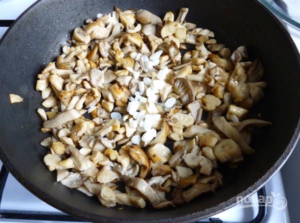 Разогрейте в сковороде растительное масло. Нарежьте произвольно вешенки, выложите их в сковороду. Обжаривайте грибы с добавлением нарубленного чеснока. Посолите и поперчите по вкусу. 