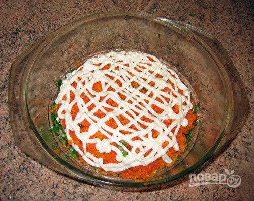 3. Заранее отвариваю морковь, после измельчаю с помощью терки и выкладываю на зелень, поливаю тонким слоем майонеза. Соленые огурцы нарезаю тонкой соломкой или кружочками, выкладываю поверх вареной морковки и смазываю майонезом. 