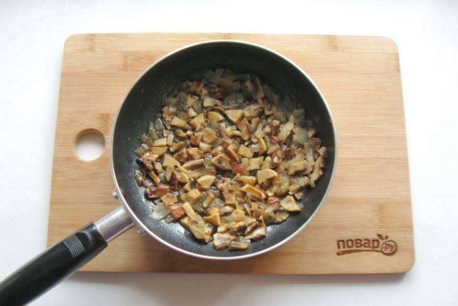 Налейте подсолнечное масло и поджарьте лук с грибами в течение 10-12 минут, перемешивая.