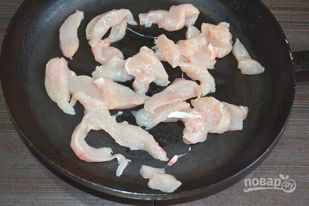 2. На сковороду с растительным маслом выложите нарезанное тонкими ломтиками куриное филе. Обжарьте до легкой корочки. 