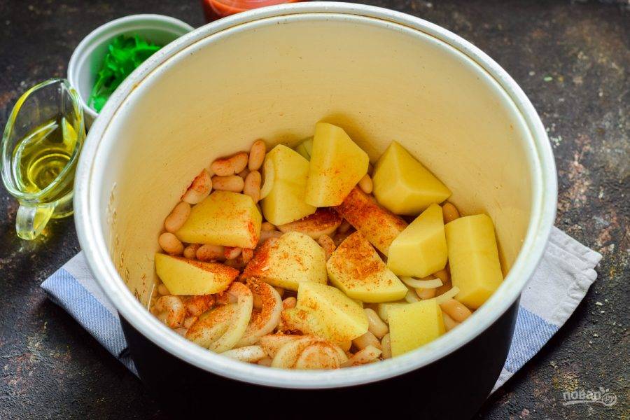 В чашу мультиварки выложите картофель, лук и фасоль. Добавьте специи.