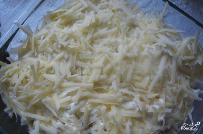 На верх запеканки кладем еще слой картошки, добавляем кольца лука и натираем твердый сыр. Заливаем блюдо сливочным соусом, который мы делали в начале. Отправляем блюдо в духовку на 40 минут. Выставляем температуру 180 градусов.
