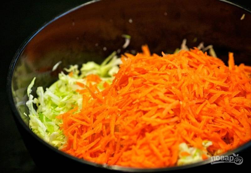 Почистите, промойте и натрите на большой тёрке морковь. Добавьте её к капусте.