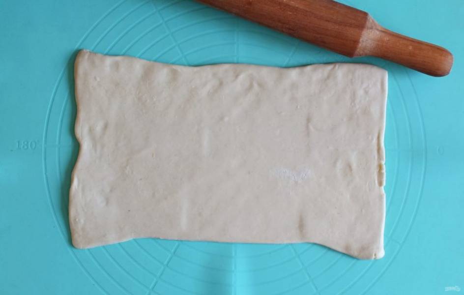 Слоёное тесто заранее разморозьте. Раскатайте прямоугольный пласт толщиной 0,5 см.