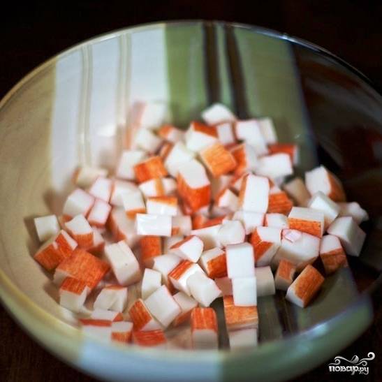 Крабовые палочки нарезаем на достаточно крупные кубики и выкладываем в салатницу.