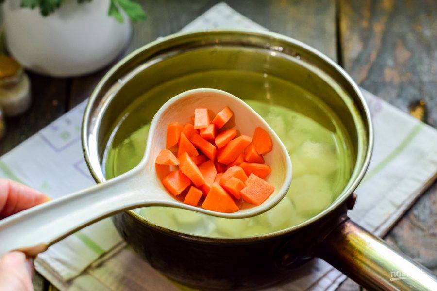 Морковь очистите и сполосните, нарежьте небольшими кусочками и добавьте в кастрюлю к картофелю.