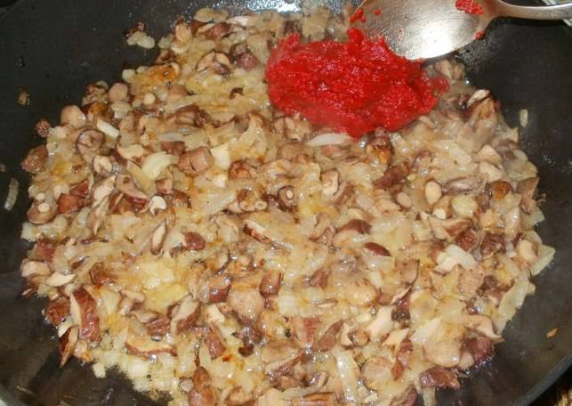Далее выкладываем лук на сковороду, жарим его до золотистого цвета, затем добавляем грибы, жарим все вместе еще пару минут, когда и грибочки станут золотистыми, добавляем к ним томатную пасту.