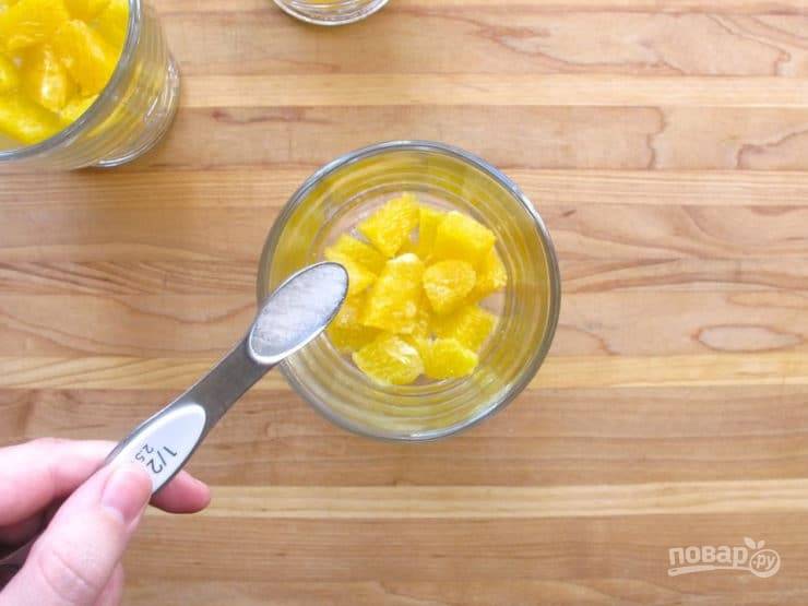 1. Апельсин нарежьте кусочками, предварительно разделив его на дольки и удалив плёнку. Выложите половину мякоти в 3 креманки. В каждую насыпьте по ложке сахара.