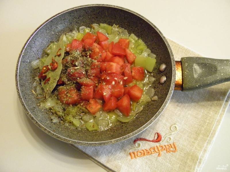 Добавьте помидор к жареным овощам, также хмели-сунели, порезанный мелко чеснок, перец острый, лавровый лист и щепотку черного перца. Протушите несколько минут до полной готовности всех ингредиентов.