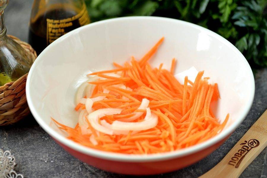 Репчатый лук нарежьте полукольцами, морковь натрите тонкой соломкой, выложите овощи в глубокую миску.