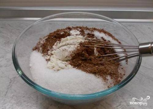 В глубокой миске надо смешать сухие ингредиенты - половину сахара, просеянную муку, разрыхлитель и соду. 