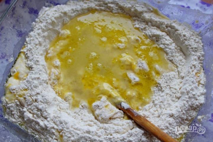 В муку добавьте яйца для теста. Перемешайте массу деревянной ложкой. Отдельно соедините воду с 4 ст. ложками масла. Влейте смесь в муку, также всыпьте соль. Аккуратно перемешайте тесто.