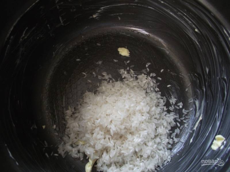 Рис промойте, чашу мультиварки смажьте сливочным маслом. Выложите рис в чашу мультиварки.