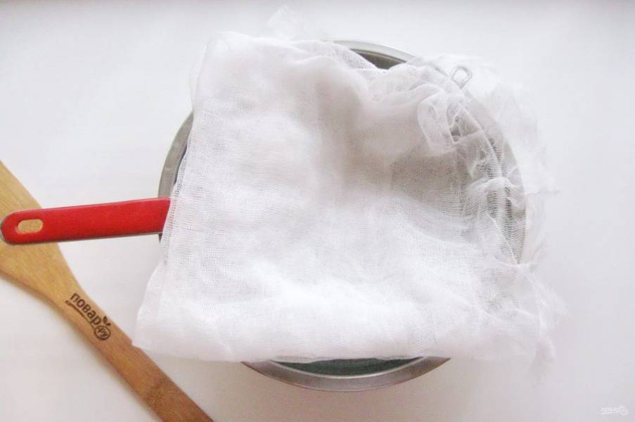 Когда кефир замерз, приступите к следующей стадии приготовления творожного крема. Дуршлаг выстелите марлей, сложенной в несколько слоев и поставьте на миску или кастрюлю.