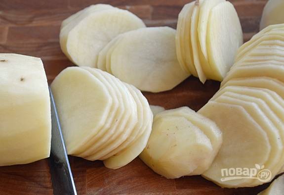 Почистите, промойте и нарежьте тонкими слайсами картофель.