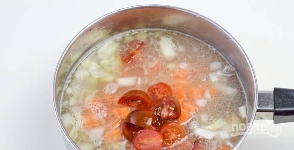 Положите в суп помидоры и морковь. Убавьте огонь и варите его до тех пор, пока рис полностью не приготовится. 