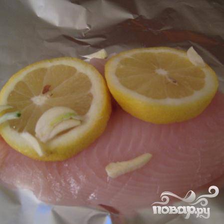 Положите на филе лимон (по 2-е шт. на 1 филе) и немного чеснока.