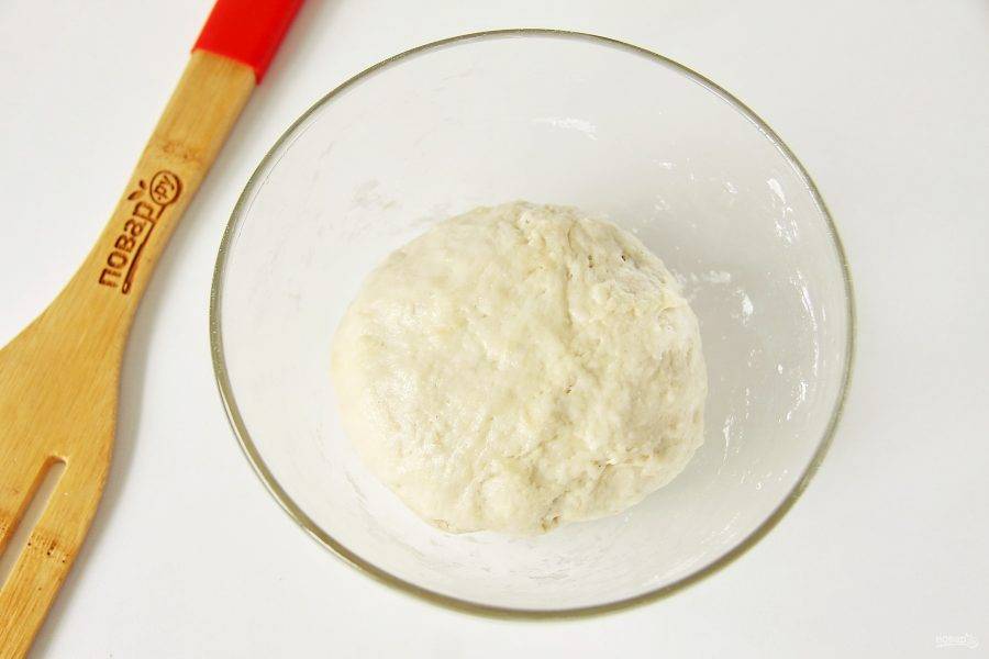 Затем руками замесите мягкое, немного липкое тесто. Соберите его в шар, смажьте растительным маслом, накройте полотенцем и уберите в теплое место примерно на час, чтобы оно увеличилось в объеме.
