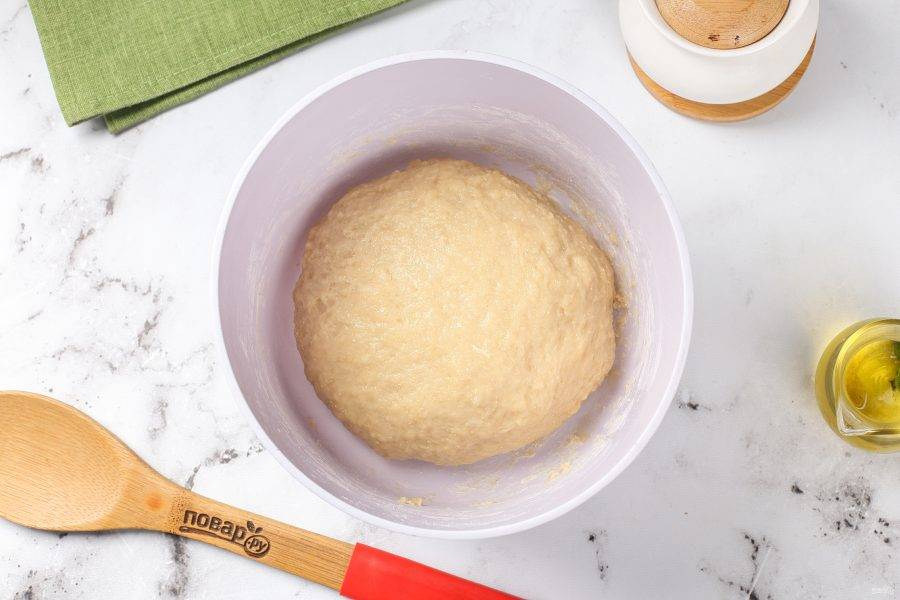 Замесите мягкое тесто, в процессе если необходимо, подсыпая ещё необходимое количество муки. Тесто получится немного липкое. Соберите его в шар, смажьте растительным маслом, накройте и оставьте в тёплом месте на 1,5-2 часа.