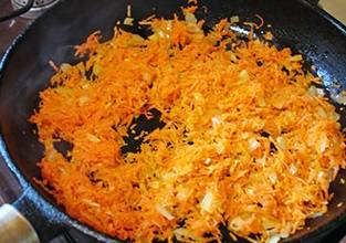 3. Натрите морковь на терке и добавьте в сковороду с луком. Обжарьте еще несколько минут.