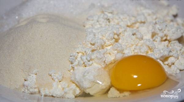 В удобной посуде замешиваем творог, яйцо, сахар и манку. Все тщательно перемешиваем до однородной массы.