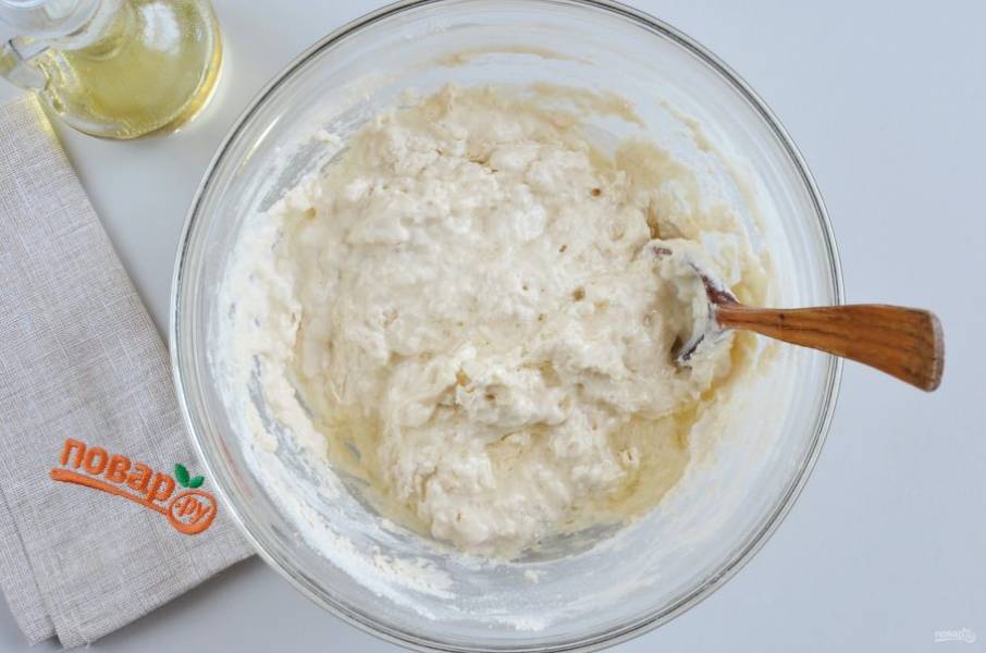 Всыпьте большую часть муки, начните ложкой замешивать тесто, в процессе влейте растительное масло.