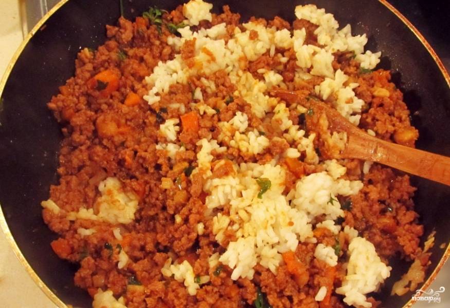 Затем добавьте петрушку и варёный рис. Тушите всё вместе, пока рис не впитает в себя сок фарша и не поменяет цвет.