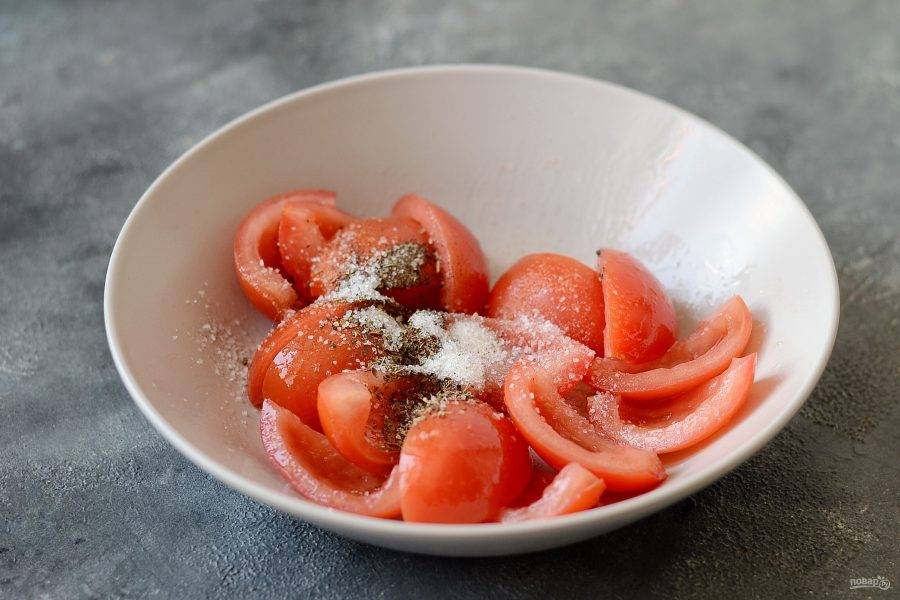 Добавьте в томаты растительное масло, перемешайте. Выложите томаты срезом вверх, посыпьте травами, сухим чесноком и сахаром, посолите и поперчите.