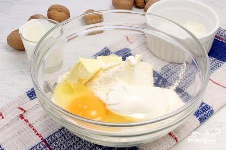 50 г мягкого сливочного масла смешайте с мукой, сметаной, разрыхлителем и яйцом. Замешайте мягкое тесто.