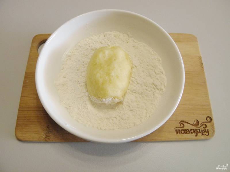 Сформируйте пирожок из столовой ложки картофельного теста, обваляйте его в муке со всех сторон.
