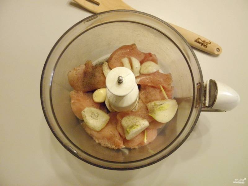 Отделите куриное мясо от кости, снимите и выбросьте шкуру. Сложите в измельчитель мясо, лук и чеснок. Добавьте по вкусу соль и щепотку молотого перца.