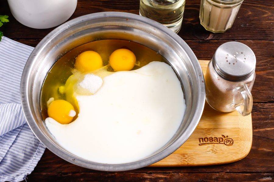 Вбейте куриные яйца в емкость, влейте кефир любой жирности и всыпьте сахар, соль. Взбейте все венчиком.
