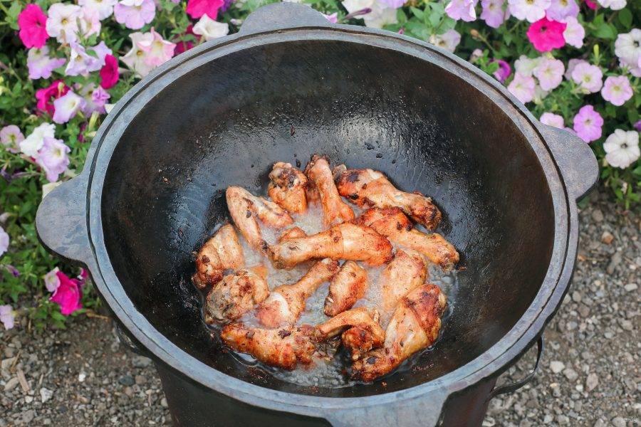 В казан с кипящим маслом выложите маринованные части курицы. Обжарьте до равномерной румяной корочки и выложите на тарелку.