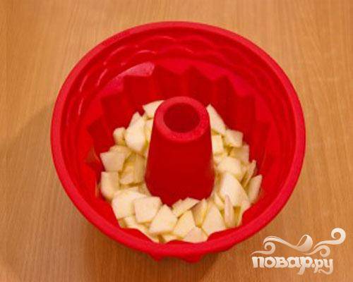 3. Маслом смазываем форму для выпечки. Немного теста выкладываем на донышко формы. Половину яблок опускаем сверху на тесто. Яблоки по желанию посыпаем корицей.